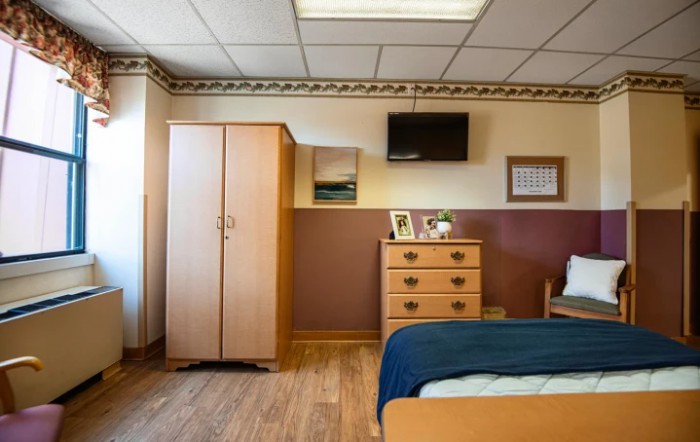 A cozy bedroom with wood furniture, including a dresser and wardrobe, and a mounted television.