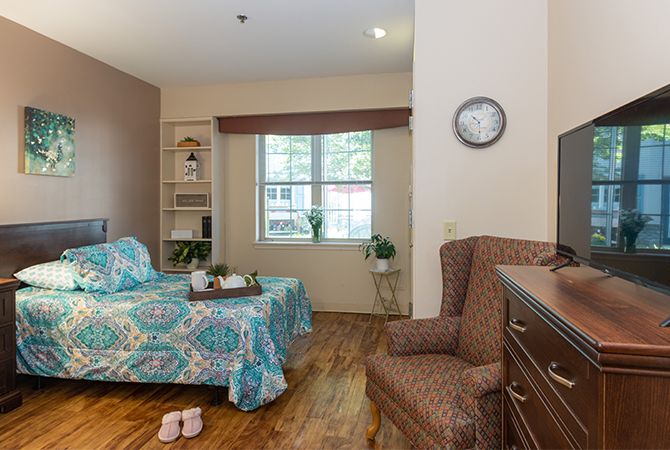 A cozy bedroom with a single bed, patterned bedding, and wooden flooring.