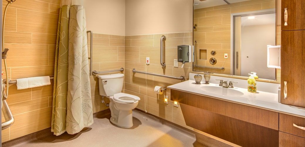 An accessible bathroom with a toilet, sink, and grab bars.