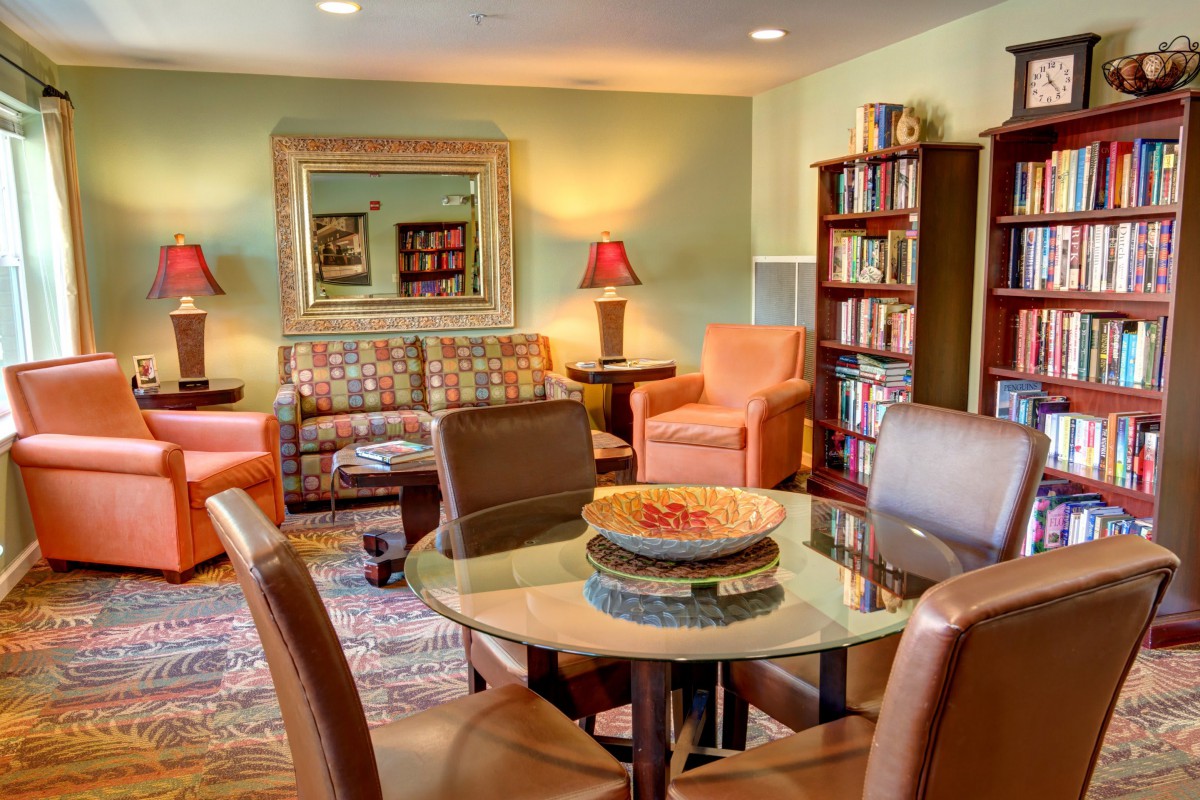 A cozy living room with comfortable seating, a bookshelf, and warm lighting.