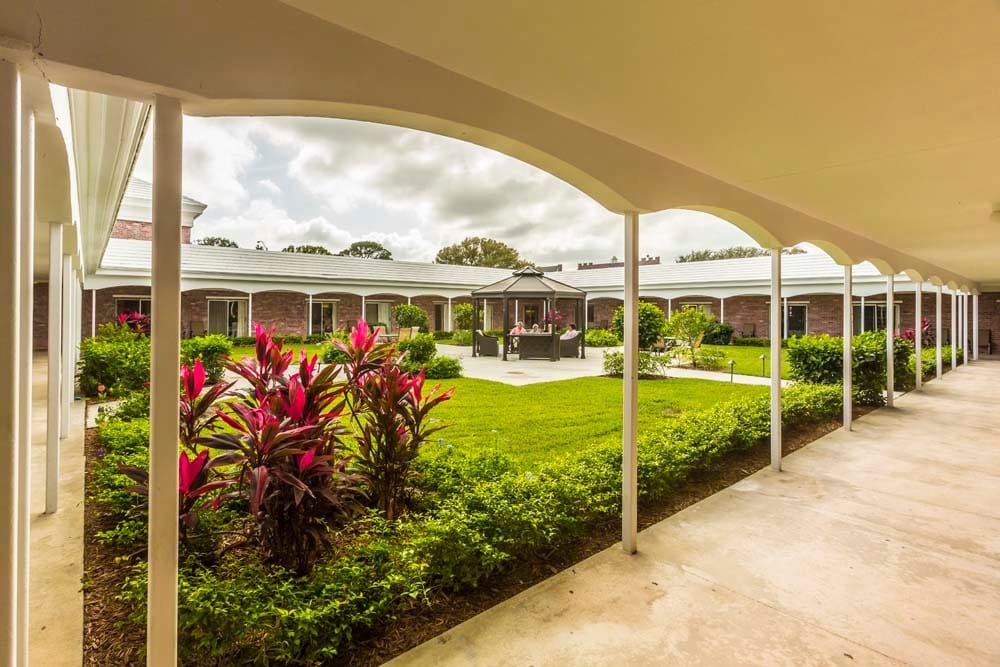 A view of a well-maintained courtyard garden surrounded by a building with arched walkways.