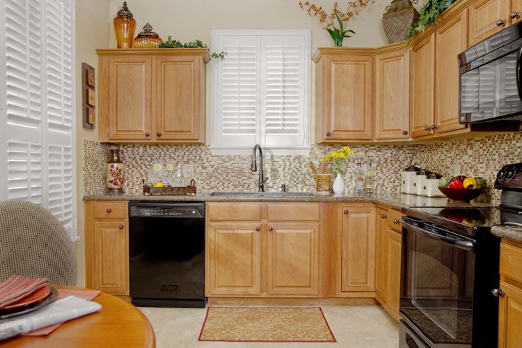 A cozy kitchen with wooden cabinets, a mosaic tile backsplash, and modern appliances.