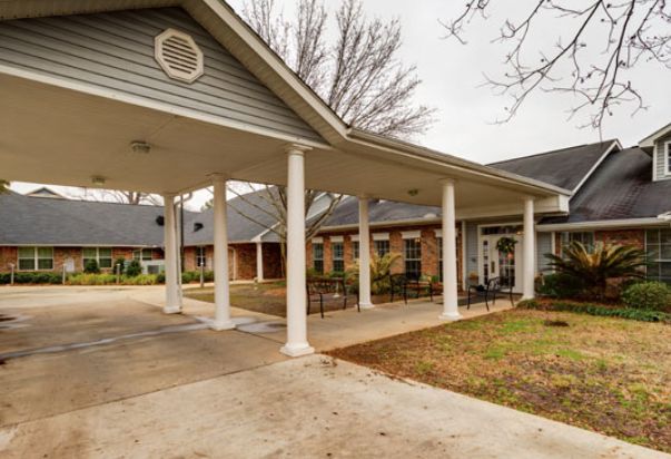 A building with a covered entrance featuring columns and a driveway.