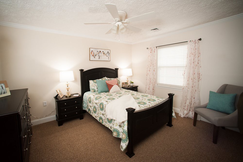 A cozy bedroom with a well-decorated bed, bedside tables with lamps, and light curtains.
