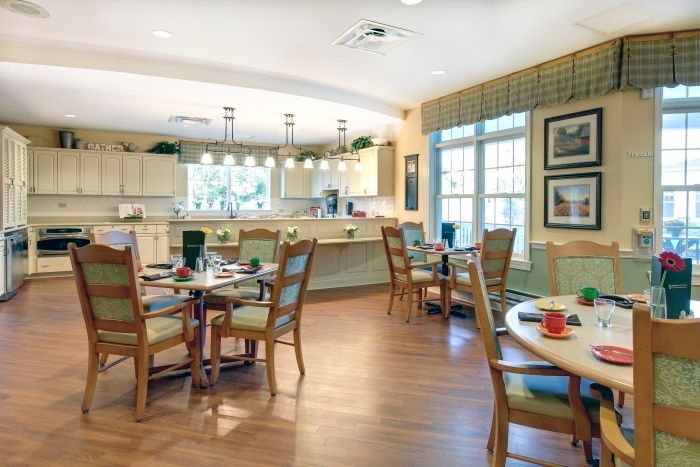 A cozy dining area with tables and chairs, connected to a modern kitchen.