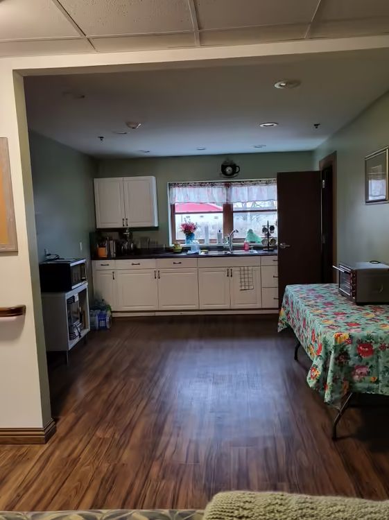 A cozy kitchen with white cabinets, a table, and appliances.