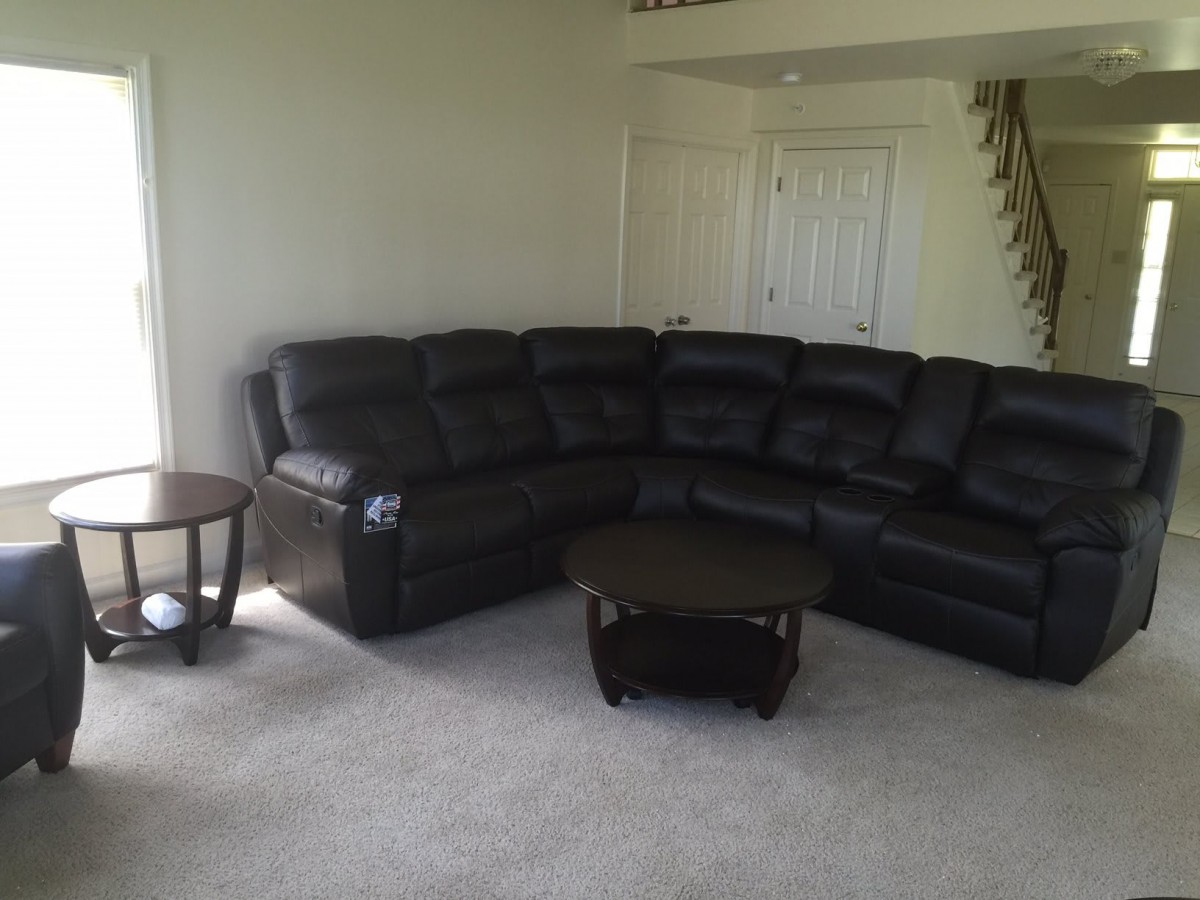 A cozy living room with a black sectional sofa and matching coffee table.