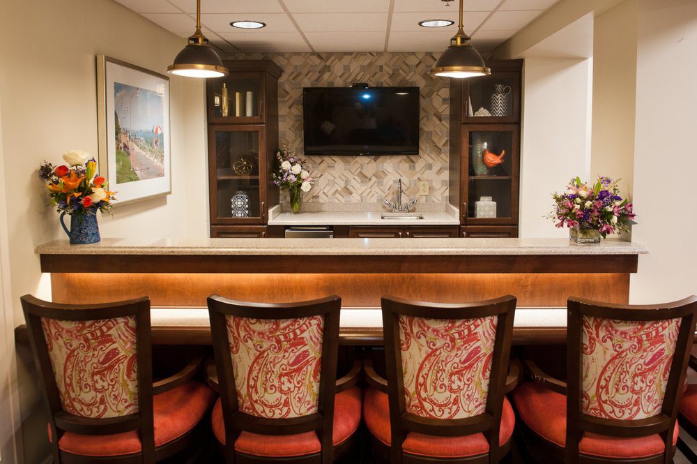 A cozy home bar setup with elegant chairs and ambient lighting.