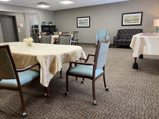 A well-kept dining area with neatly arranged tables and chairs, adorned with tablecloths and wall art.