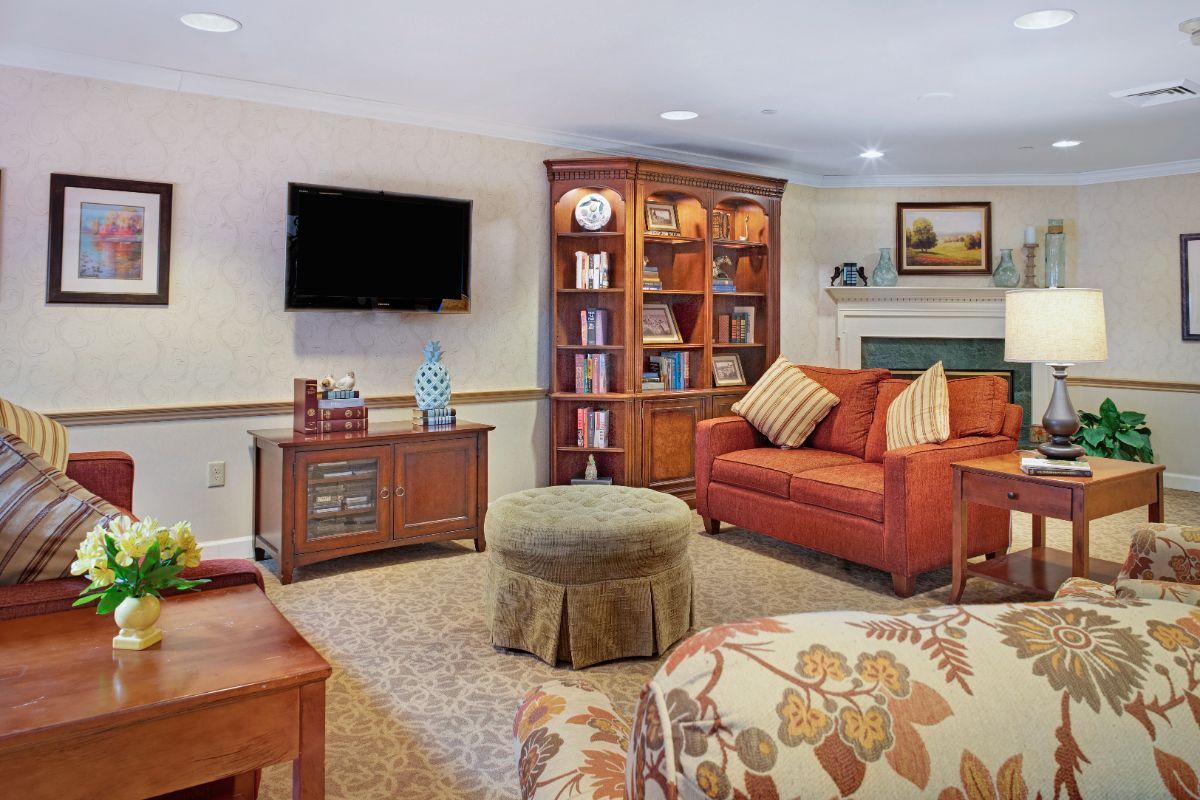 A cozy living room featuring a comfortable sofa, wooden bookshelf, and a wall-mounted television.