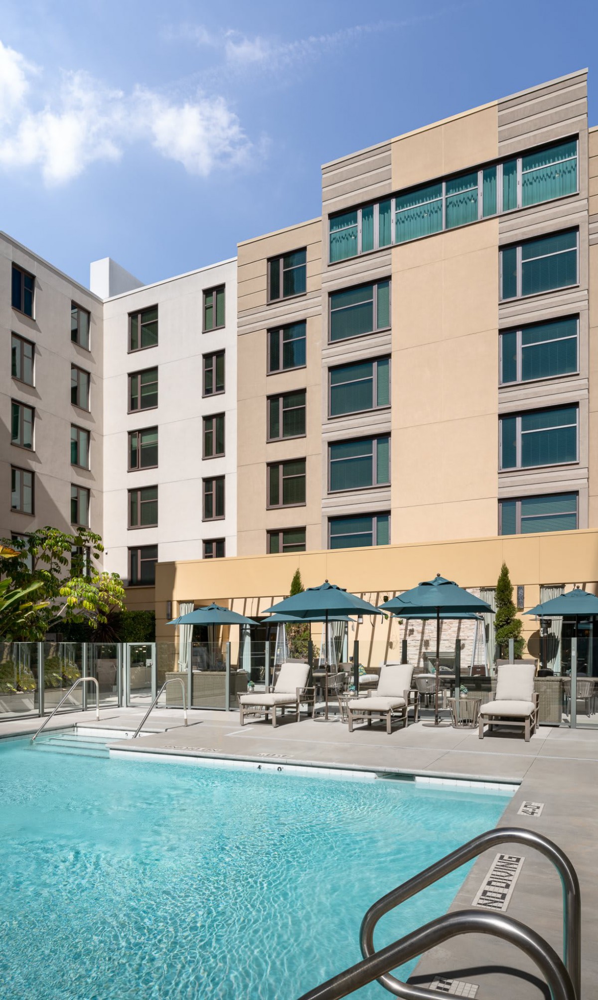A modern hotel with a pool and outdoor seating area.