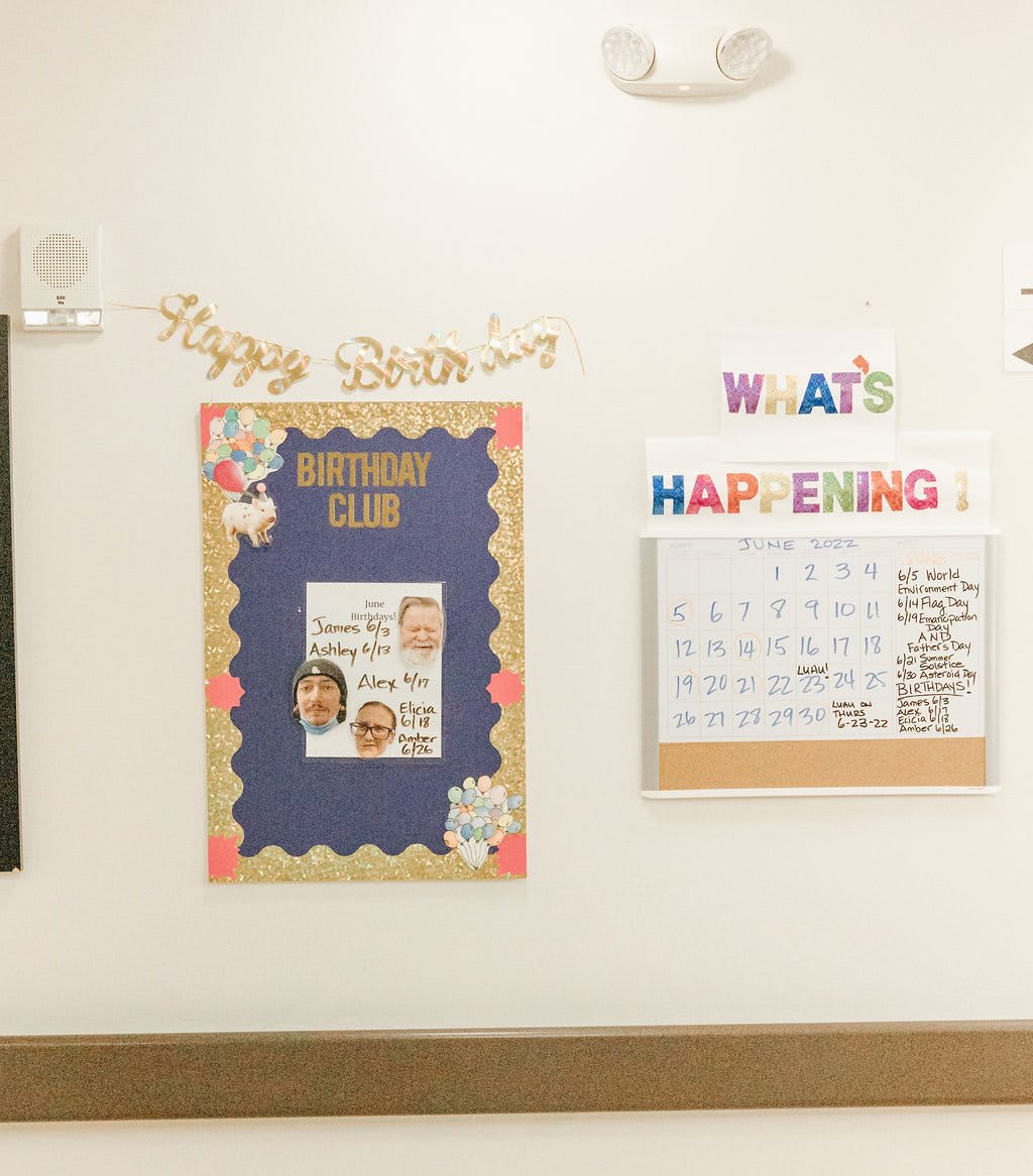 Classroom wall featuring a bulletin board and calendar for upcoming events.