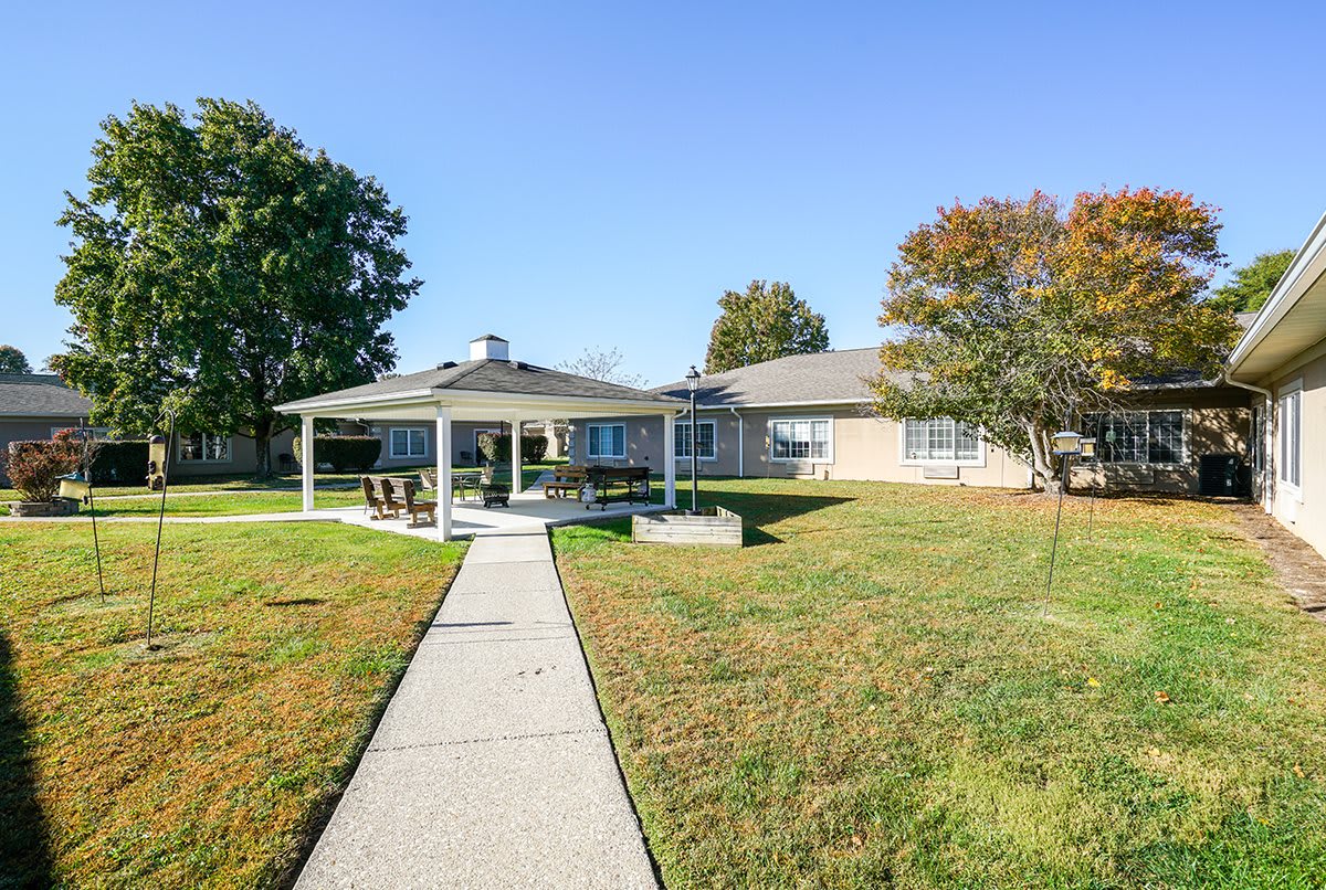 A cozy house with a spacious backyard featuring a covered patio and a well-maintained lawn.