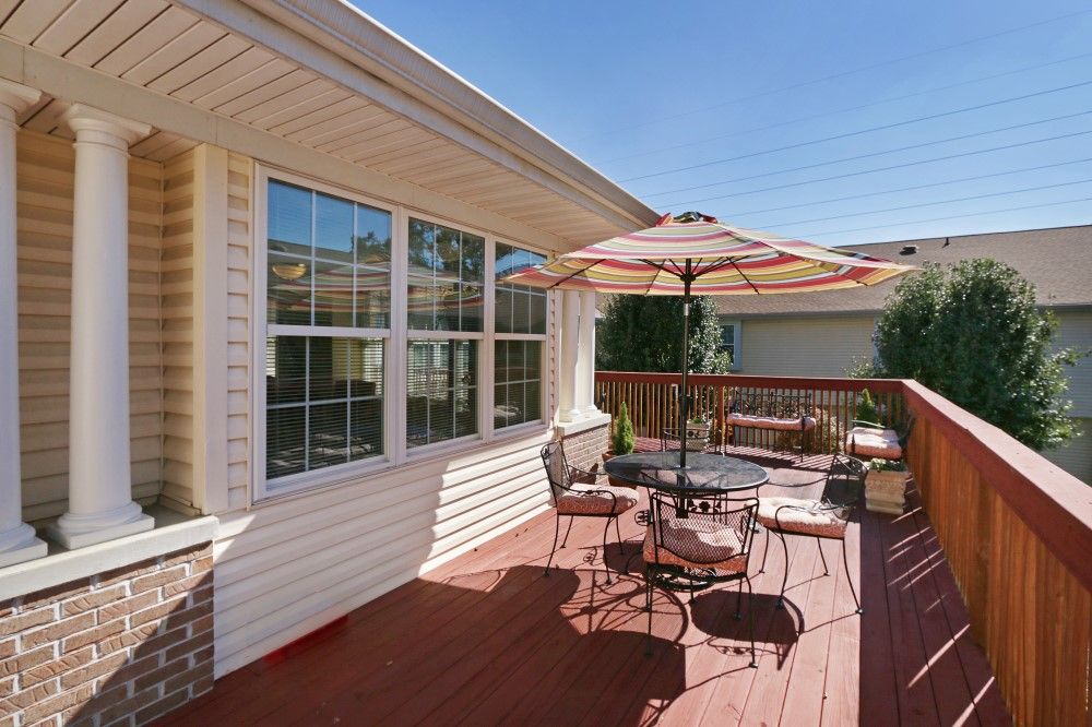 A sunny wooden deck with outdoor furniture and an umbrella.