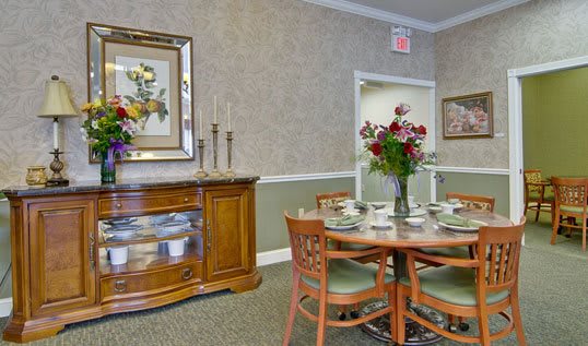 A well-decorated dining room featuring a wooden table set with chairs and floral arrangements.