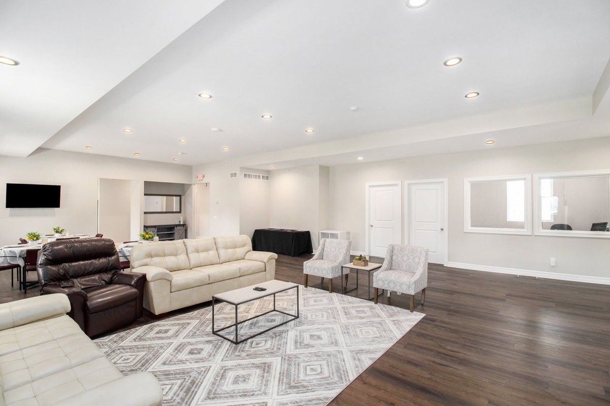 A spacious and modern living room featuring comfortable seating, a patterned rug, and bright overhead lighting.