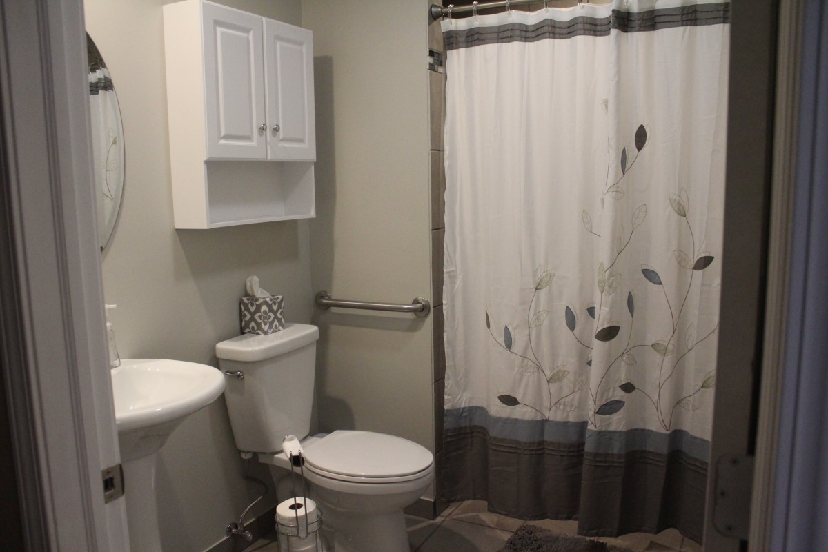 A neatly organized bathroom featuring a toilet, wall-mounted cabinet, and patterned shower curtain.