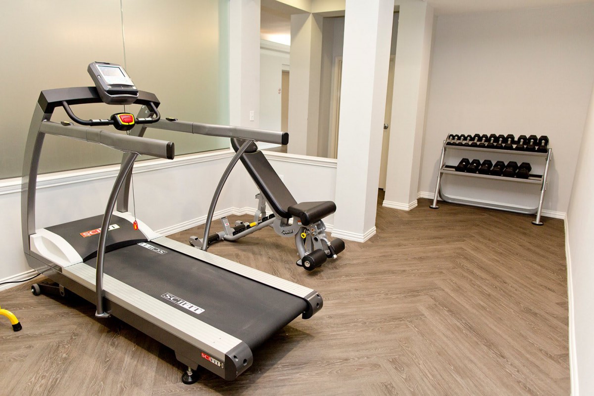 A home gym with a treadmill and weight bench, perfect for a workout session.