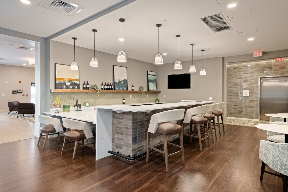 A modern kitchen interior featuring a large island with bar stools and pendant lighting.