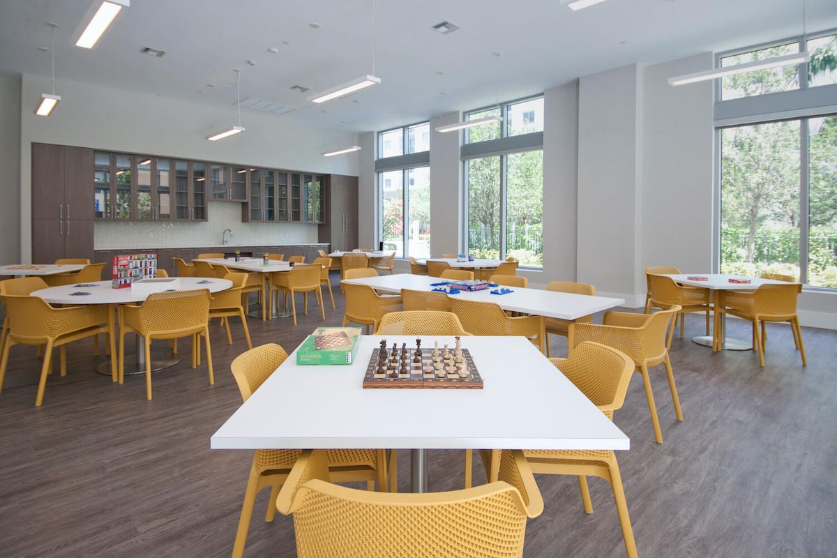 A modern classroom with tables and chairs arranged, featuring a chessboard on one of the tables.