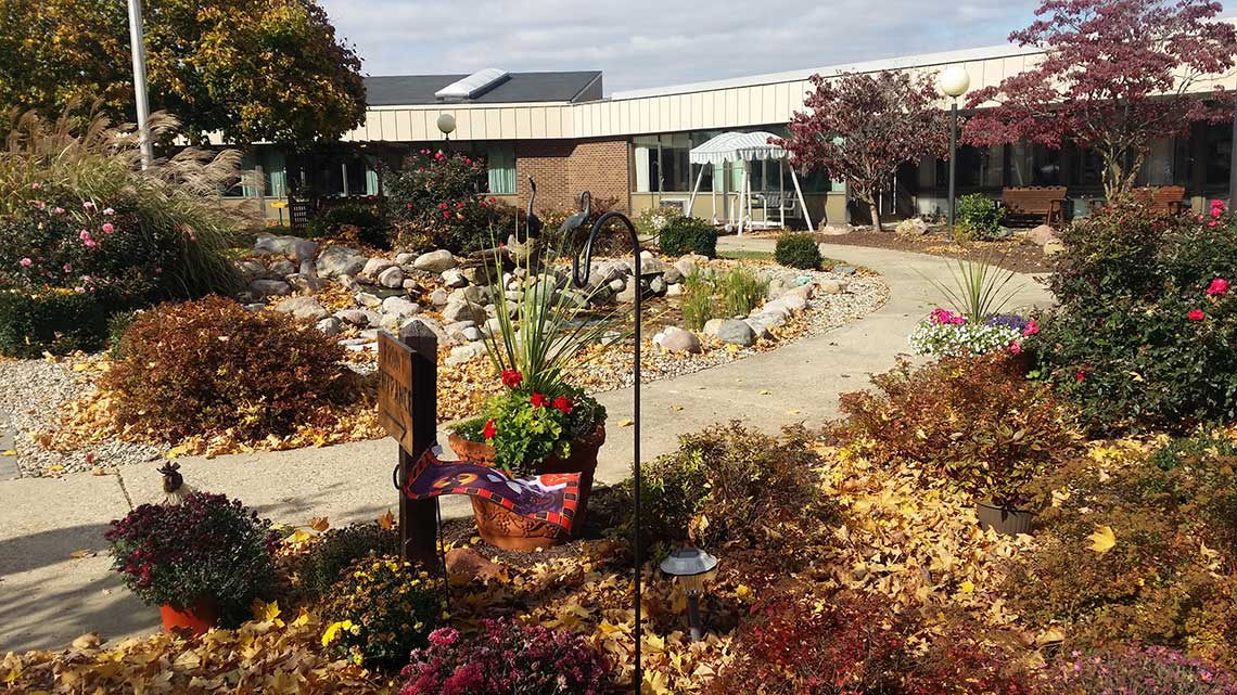 A scenic view of a building surrounded by an autumn garden with colorful foliage and a winding pathway.