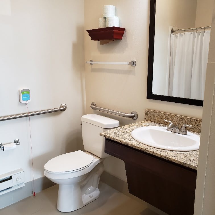 Accessible bathroom with grab bars and a shower curtain.