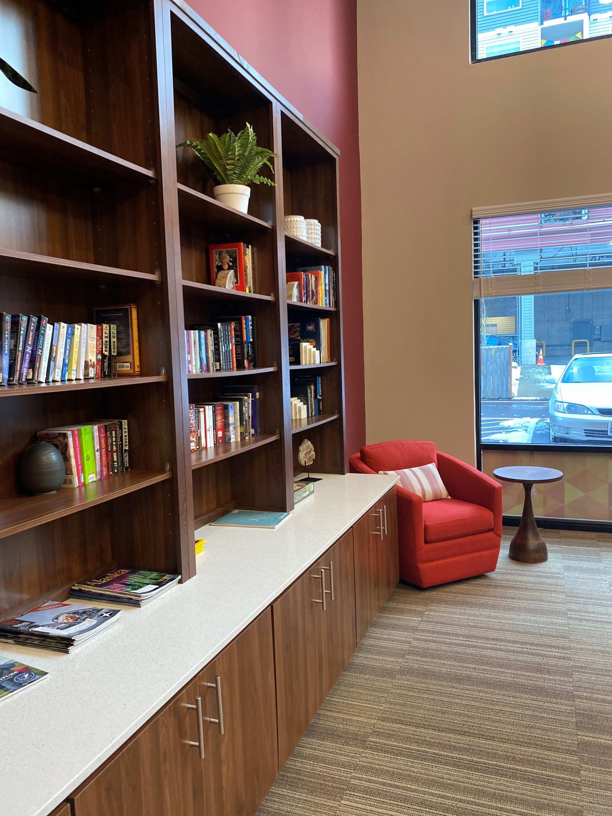 A cozy reading corner with bookshelves and a red armchair next to a window.