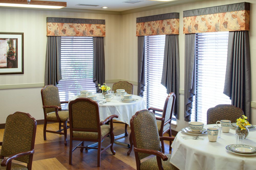 A cozy dining room setup with round tables, chairs, and large windows.
