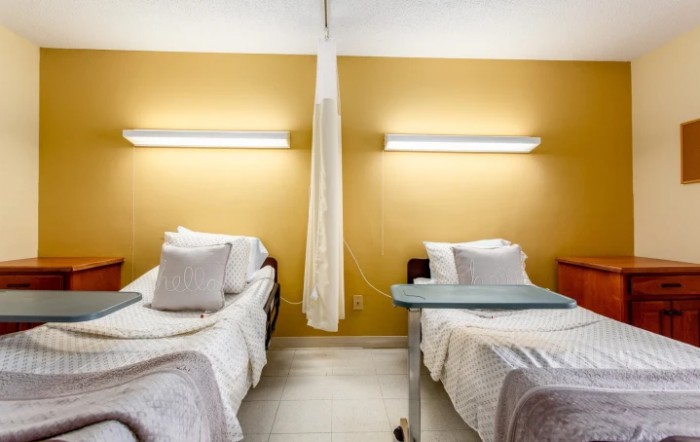 A hospital room with two beds separated by a curtain.