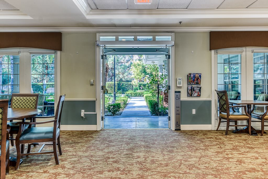 A spacious interior with a carpeted hallway leading to an open doorway overlooking a garden.
