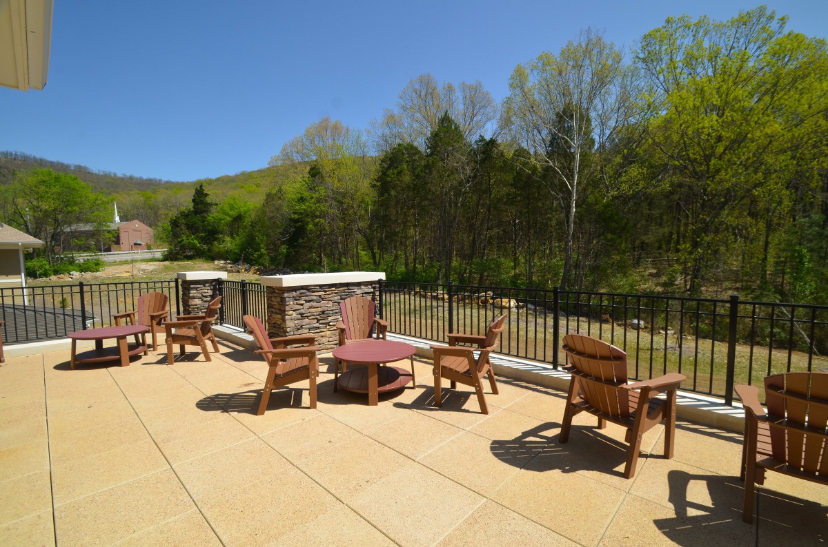 A scenic outdoor patio with wooden chairs and tables overlooking a natural landscape.