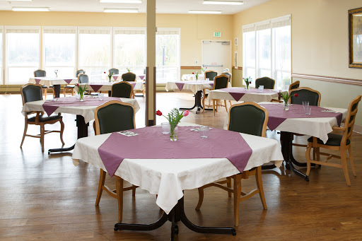 A spacious dining area featuring elegantly set tables with purple tablecloths and floral centerpieces.