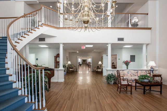 Spacious lobby with a grand chandelier, staircase, and elegant furnishings.
