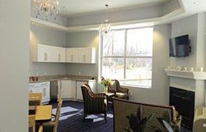 A bright and modern kitchen interior with white cabinets, a large window, and elegant seating.
