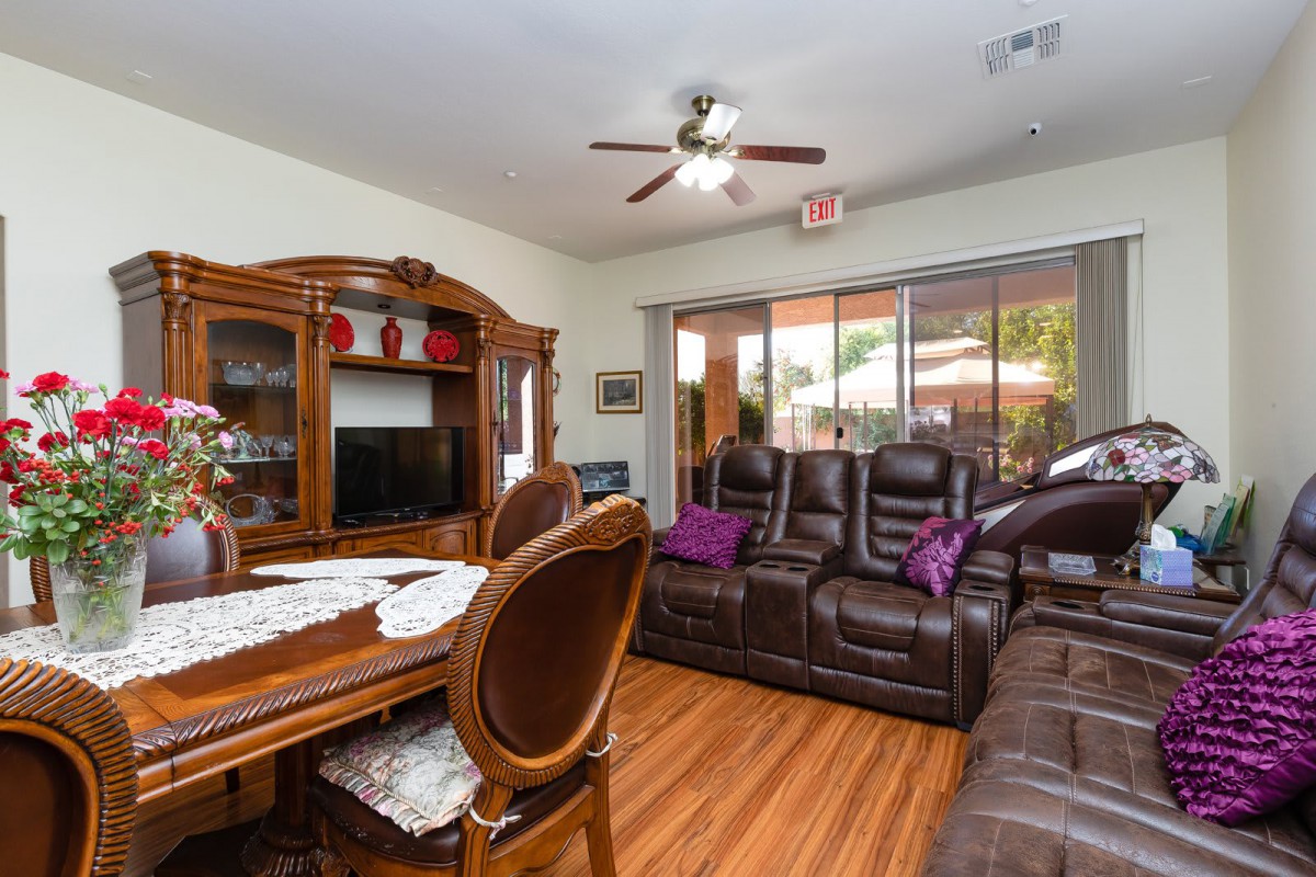 A cozy living room featuring wooden furniture, a dining table, and comfortable couches facing a television.