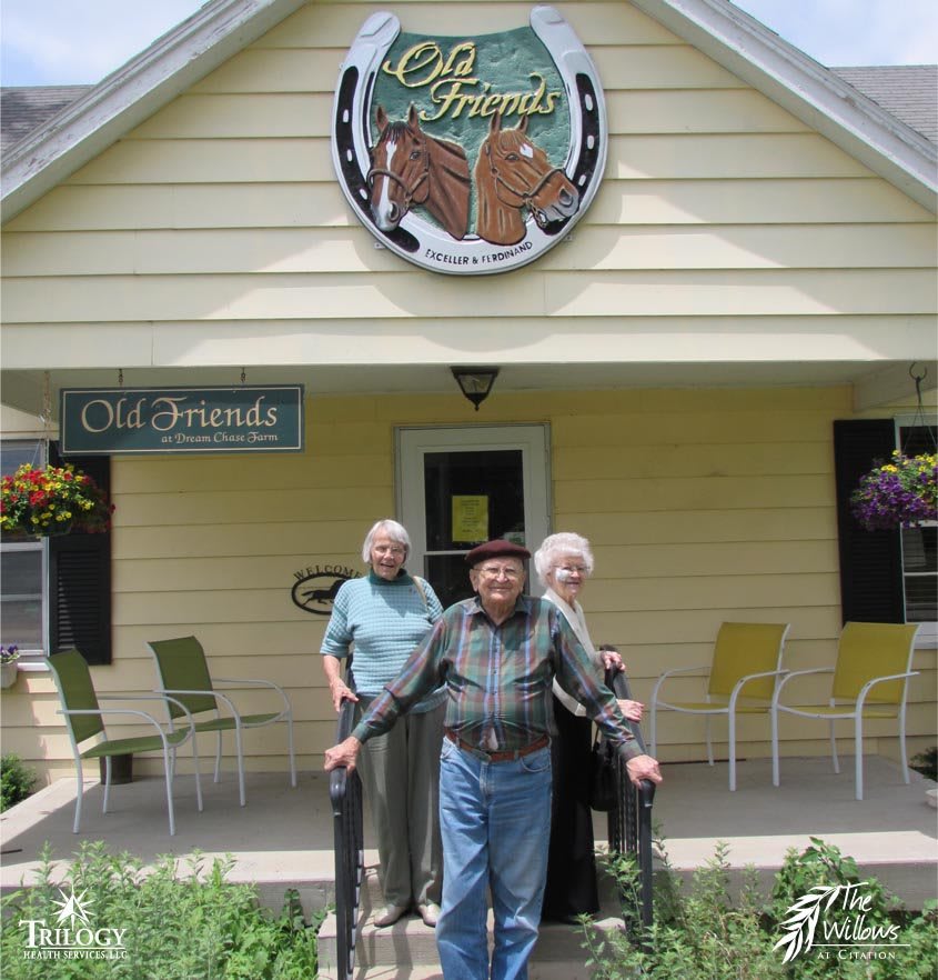 A group of elderly people standing in front of a building with a sign above the entrance.