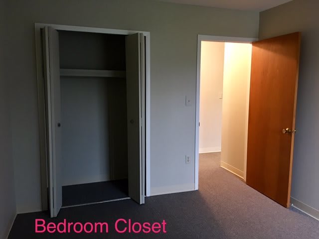 An empty bedroom with an open closet and a doorway.