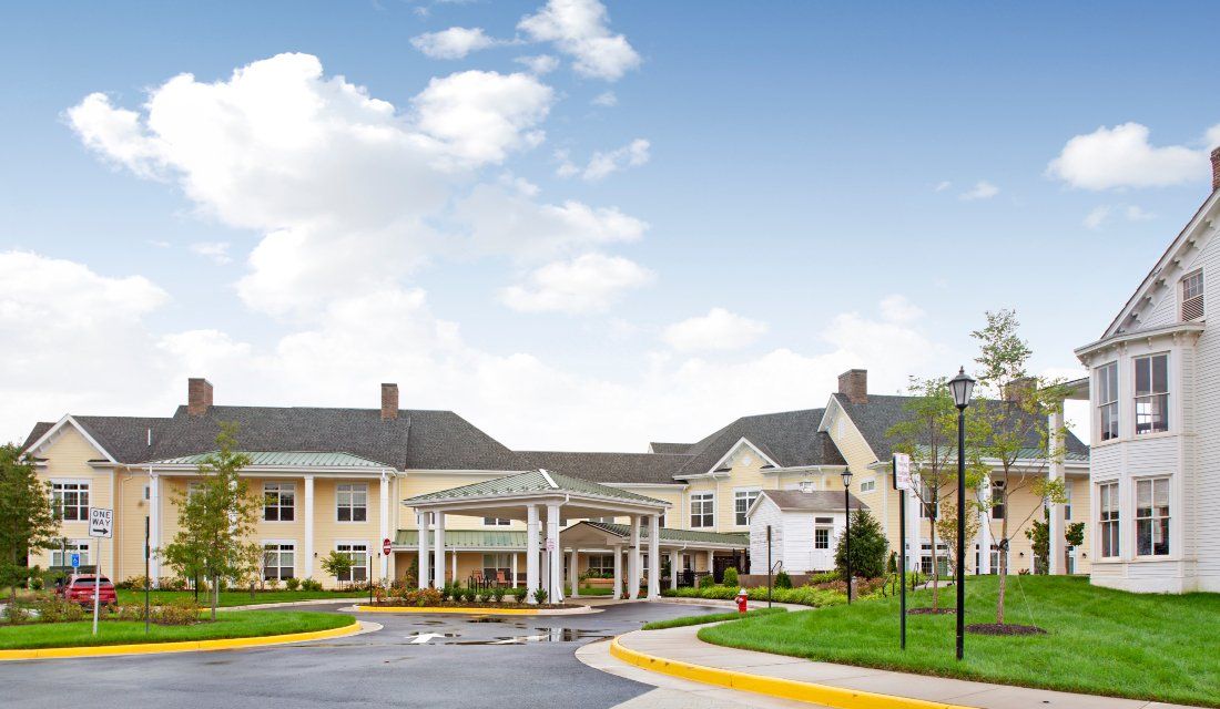 A large residential building with a driveway and clear blue sky.