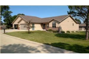 A suburban single-story house with a well-maintained lawn and driveway.