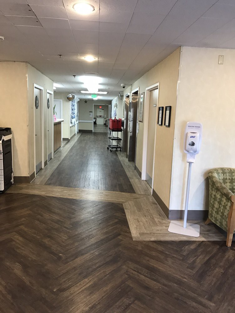 A clean and empty hospital corridor with a sanitizer dispenser.