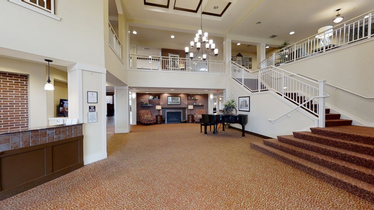 A spacious lobby with a grand piano, chandelier, and modern interior design.