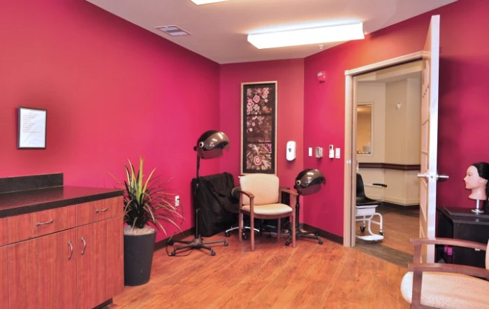 A cozy salon interior featuring vibrant red walls, seating, and hairdryers.