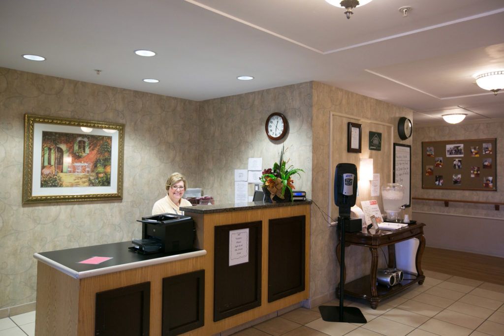 A reception area with a desk, a woman working on a computer, and wall decorations.