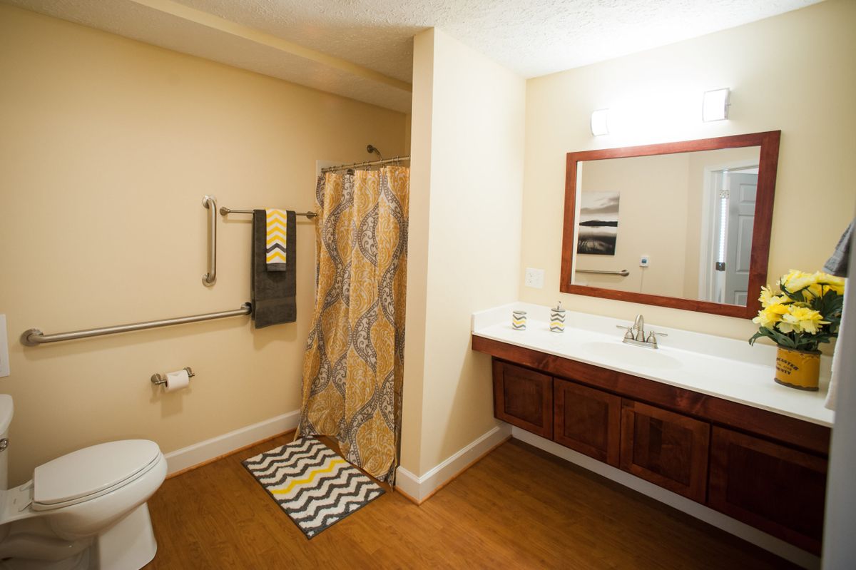 A spacious bathroom with a shower, vanity, and towel rack.