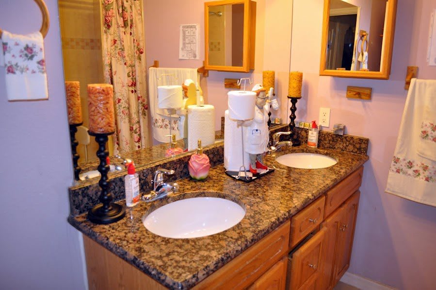 A well-decorated bathroom with a double sink vanity and candles on the countertop.