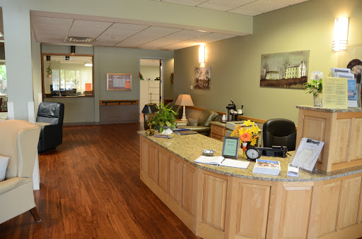 A welcoming reception area with a wooden desk, plants, and a warm ambiance.