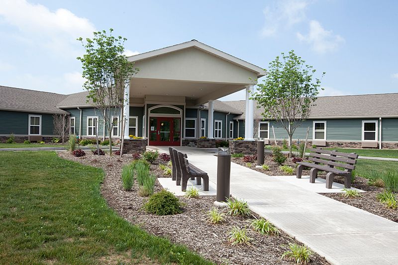A well-maintained building entrance with a landscaped garden and benches.