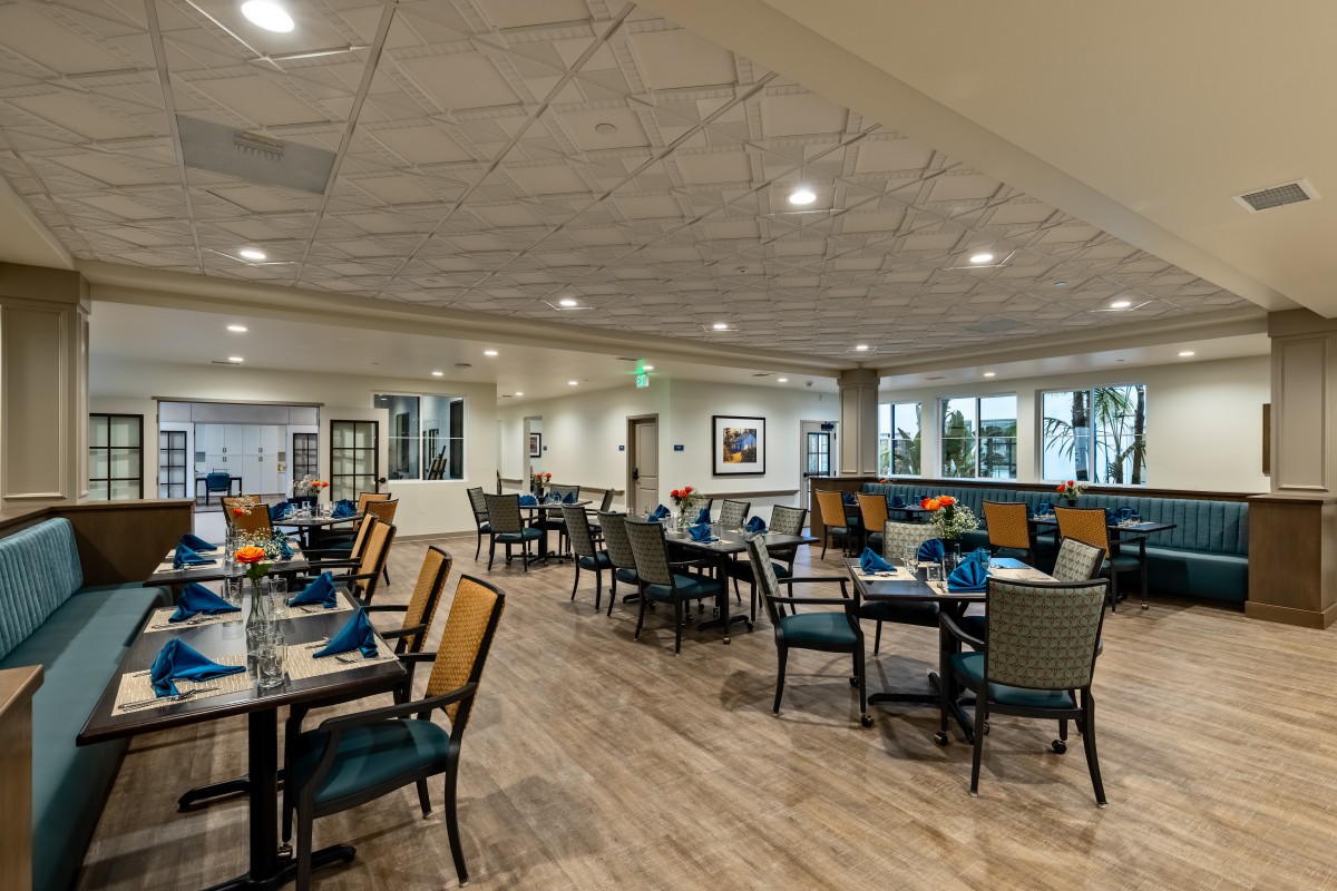 A spacious and well-lit restaurant dining area with neatly arranged tables and chairs.