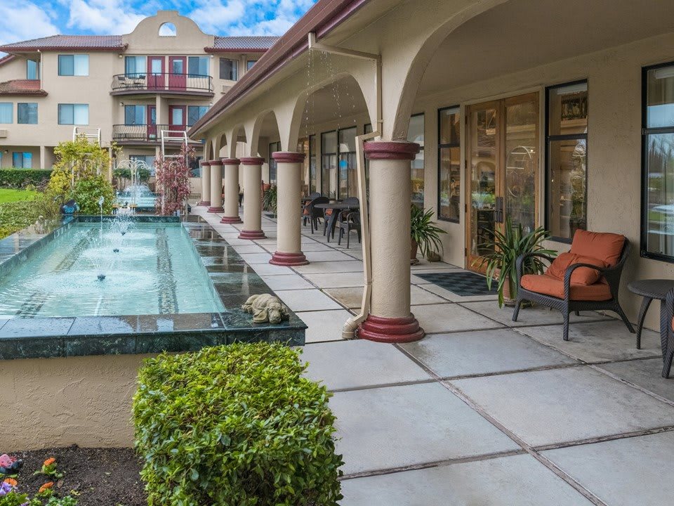 A serene courtyard with archways, outdoor seating, and a water feature.