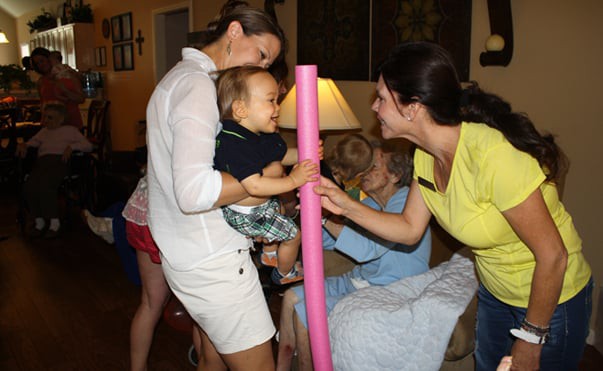 A group of people, including a child, are gathered indoors sharing a joyful moment.